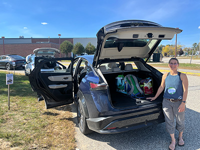 person smiling standing next to car with trunk and doors open