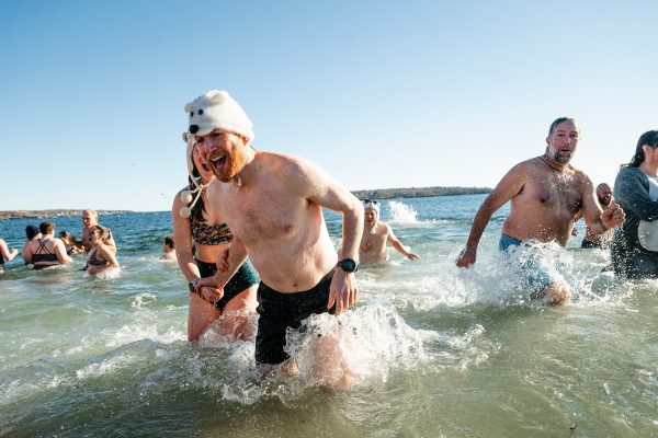 people in bathing suits running out of icy ocean water