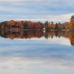 fall colors in trees along edge of smooth flat lake