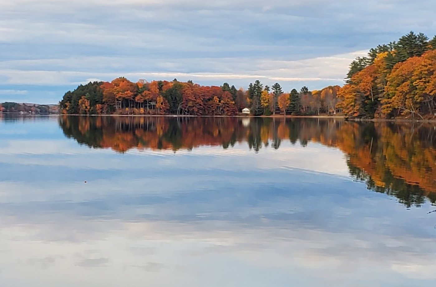 fall colors in trees along edge of smooth flat lake