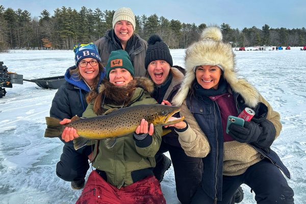 women smiling and holding fish on ice