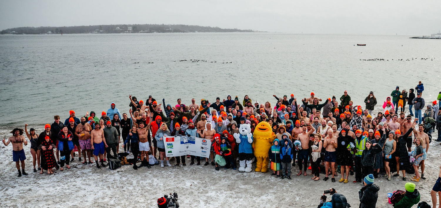group of people on beach posing for group pic in front of ocean