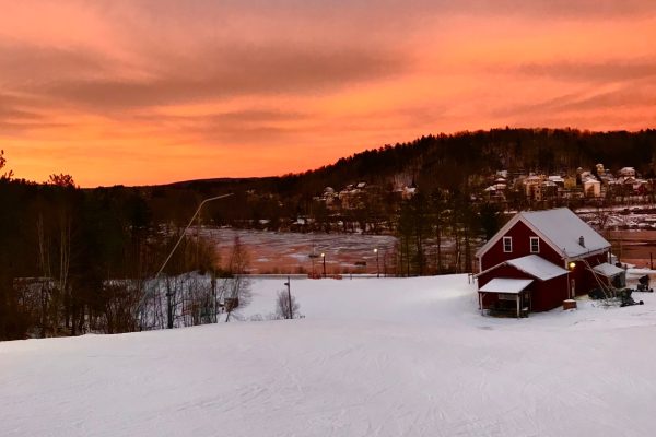 sunset over ski lodge and snow-covered slopes
